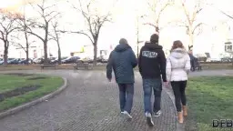 Brünette Frau zwischen zwei Männern auf Parkweg